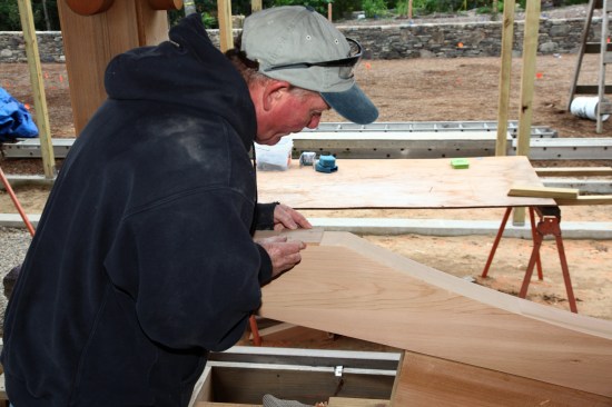 To locate the holes for the attachment screws, a crew member places a small template on the flat bottom surface of the beam.