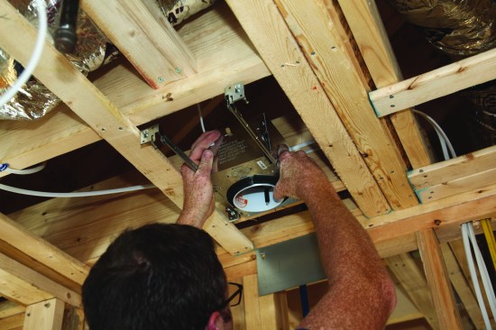 To install the ceiling can, the author lines it up on one of his centerline marks.