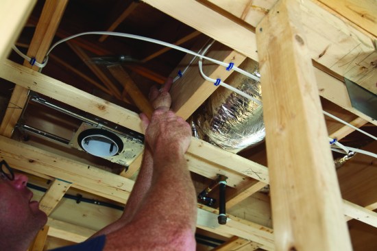 Finally, he pulls the slack out of the switch leg and staples the cable to the joist.