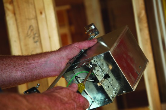 A slotted screwdriver removes the knockout for the switch leg.