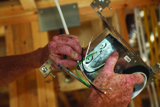 After stripping back the outer jacket of the switch leg, the author feeds the cable into the box where a spring-loaded cable clamp secures it in place.