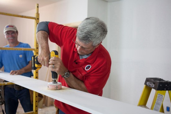 The author drills a 4-inch diameter hole at the marked location to accommodate the electrical box for the LED fixture.
