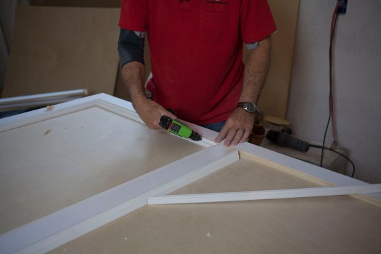 The author glues and pins the lengths of panel mold along the inside edge of the panel frame.