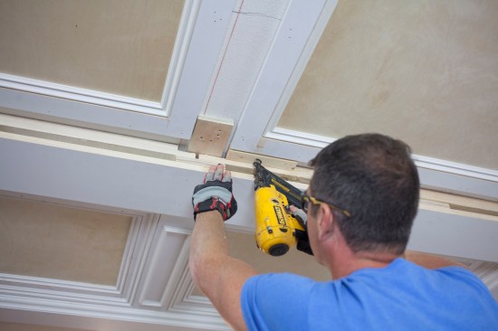 A crew member nails the blocks into the space between the panels and the major beam.