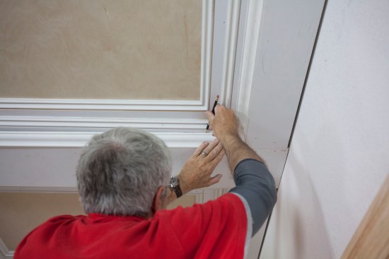 To compensate for an out-of-level ceiling in one part of the room, the author marks the section of molding that needed to be tweaked.