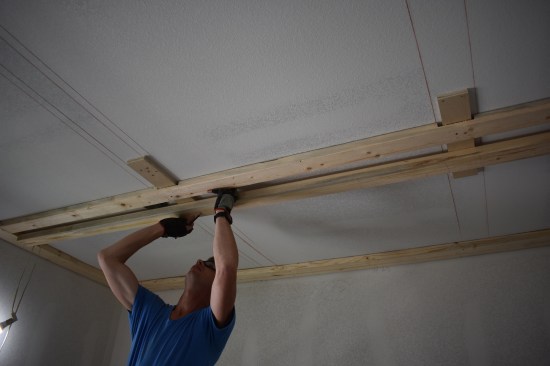 A double row of 2x4s provides nailing for the 9-inch wide major beam that has to be notched around the nailing blocks. Here a crew member marks the area of the 2-by to be nothched.