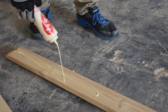 Before the 2x4 goes onto the ceiling, a generous bead of glue is slathered onto the board.