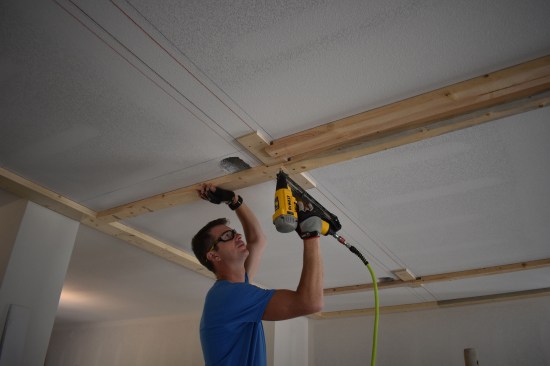 With the notch cut, a crew member tacks the ends of the 2x4 nailers to the plywood blocks. Later he drives screws to complete the attachment. 