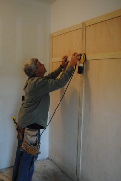 Because the panel is assembled face down, the author gives the frame joints a light sanding. 