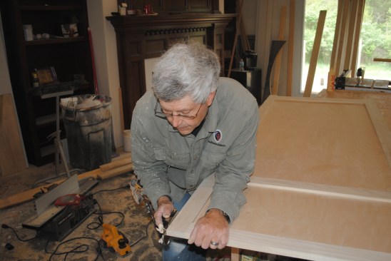 The author cuts the panel frame to the scribe line with a block plane held at a slight bevel. 
