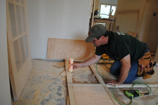 Before dropping the panels into the frame, a crew member carefully applies a bead of glue to the rabbet and spreads it thin to avoid squeeze out.
