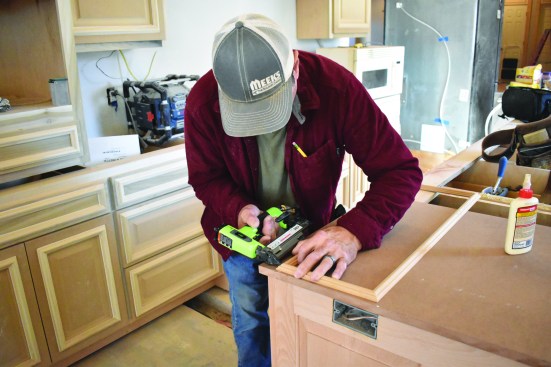 To finish off the panel, the crew member pre-assembles a decorative frame of panel molding, gluing and pinning the corners.