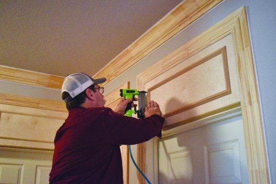 Using a gauge block to space the panel molding frame away from the door trim, the crew member attaches the frame to the transom panel. The entire door assembly is then ready for paint.