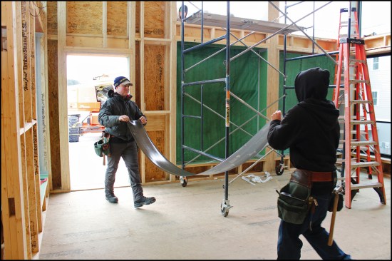 Prior to installing the big windows, the crew cuts Zip System Stretch Tape flashing to length inside. Both Zip System Stretch Tape and regular Zip System Tape were used to flash the building’s window sills.