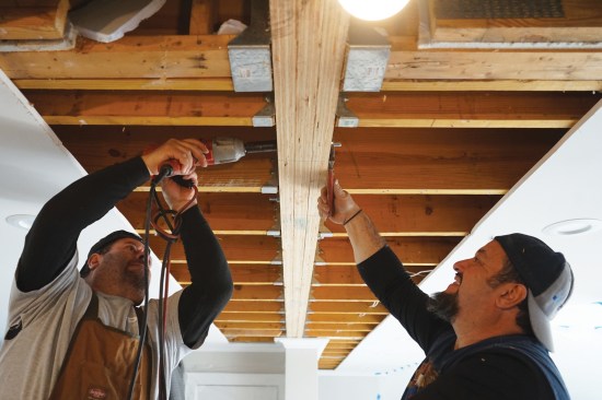 Ernesto and Toby Bonilla of Great Lake Builders worked together to tighten the nuts, drawing the beam plies together.