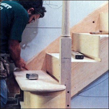 Figure 9: To install treads, the author first cuts them approximately to length — to within scribing range. He then puts them each in place temporarily, making sure the overhang along the front is even. After setting a scribe to the distance between the nosing return and the face skirt, he marks that dimension against the wall skirt. On steps with newel posts, he also has to scribe around the newel post.