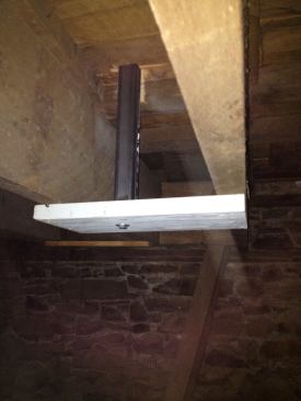 In the basement, my helper bolted a 2x8 block to the bottom of each post. While I kept the posts perfectly plumb with a level, he screwed the blocks to the bottoms of the floor joists.