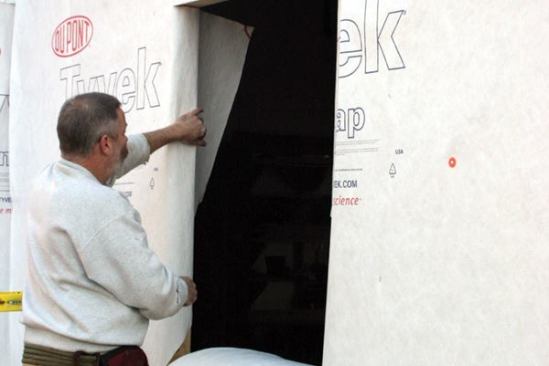 Secure the Housewrap
Next, I fold the flaps onto the jambs, trim them a bit shy of the interior face of the studs, and tape them to the framing. 
Note: This makes the gap at the jambs much easier to foam.