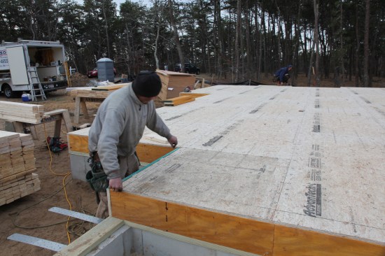 The crew snaps a line across the deck to complete the original rectangle. That line gives a layout line for the jog in the foreground, and it also provides a secondary reference line for laying out the other walls across the front side of the house.
