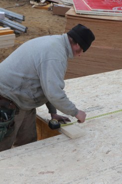 The crew pulls a measurement from the perpendicular wall at the opposite end of the house to mark the last jog wall.