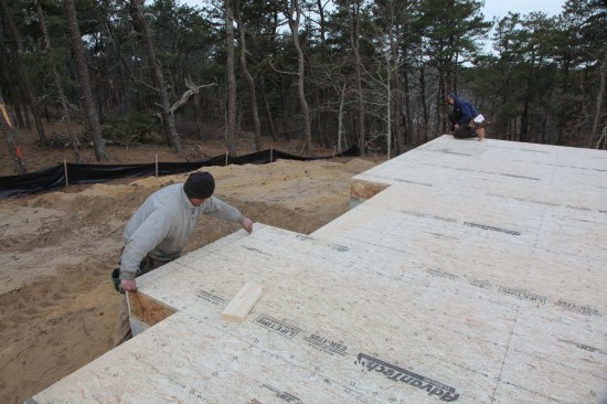 On the opposite end of the house, the crew snaps a chalk line for the wall that marks the other perpendicular side of the rectangle. On this side, the line extends through the fireplace bump-out in the foreground.