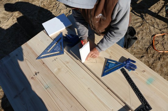 The drawing also shows the rafter-tail cuts along with the placement of the subfascia and crown backer. While transferring the layout to the pattern rafter, the crew double-checks the details.