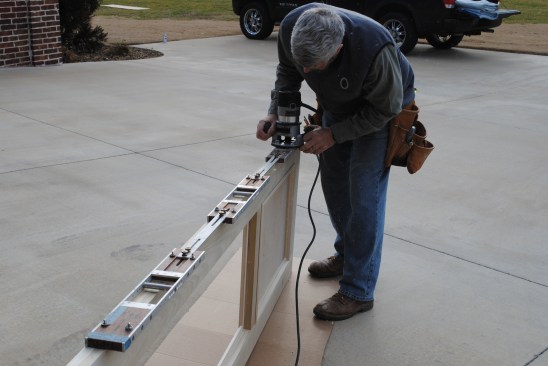 After scribing the stationary panels to fit, the author routs the hinge mortises for the operable panels.