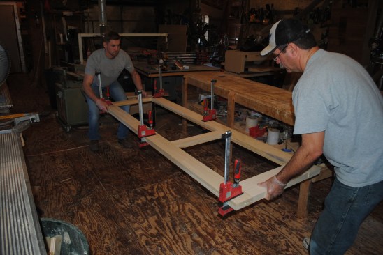 To ensure that the door turns out flat, the crew places the assembly on the on the flat surface of the floor after clamping the frames together at the corners, .