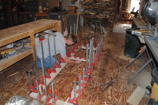 The crew adds clamps every 6 inches or so around the entire perimeter of the door, and then wipes off the excess glue with a damp cloth.