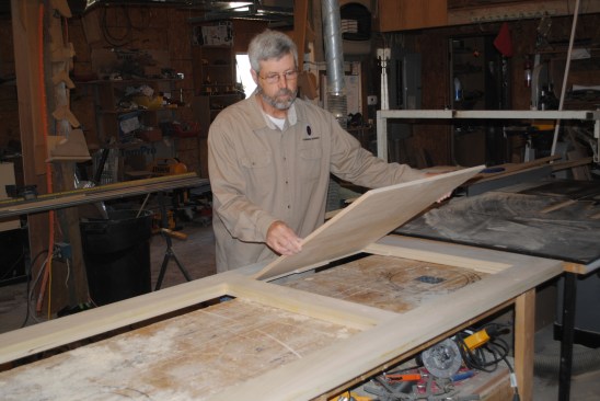 The author tacks temporary blocks to hold the plywood panel in the center of the opening, and then drops the panel into place.