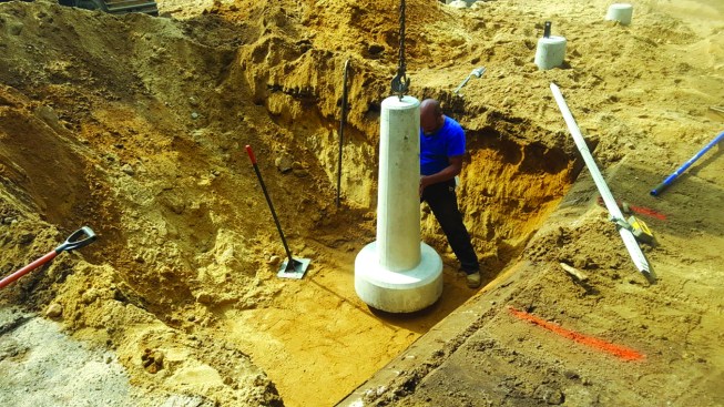 The site crew dug the hole for each precast footing individually, compacting the base of the hole and using a laser level to set the elevation.