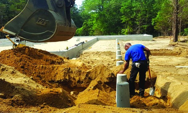 Backfilling in lifts and compacting between each layer locks the footings in place.