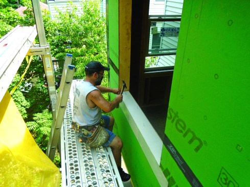 The flashing extends 6 inches beyond the opening on either side. A length of beveled siding pitches the sill for drainage.