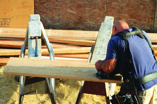 Using a series of cuts made with a circular saw, a crew member cuts the plates to go on top of the curved steel beams.