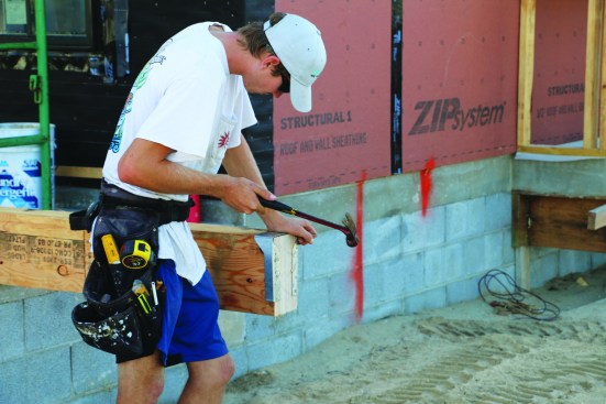 A crew member nails concealed-flange hangers to the flush beam.