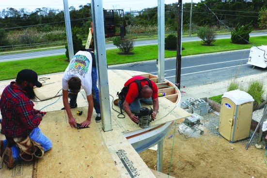 To provide the base for the waterproof fiberglass layer that will protect the areas below the porch, the crew nails down OSB subfloor, routing the curve around the perimeter with a bearing-guided bit.