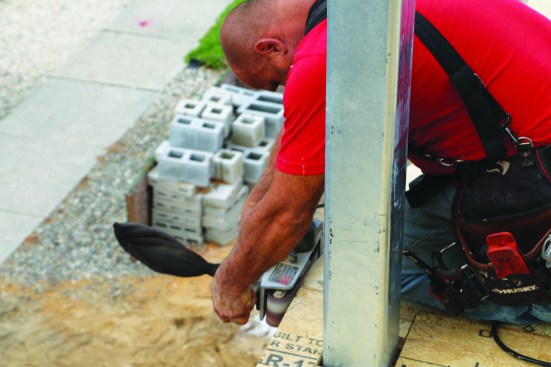 Then a crew member smooths the edge of the cut sheathing with a belt sander.