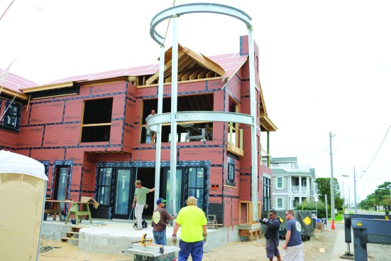 With the connections kept loose for adjustment, a crane raises the frame and sets it on the slab.