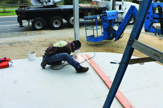 The fabricator tack-welds the bottoms of the columns to the steel plates to keep them in place during adjustment.