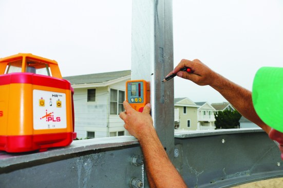After bracing the frame and tightening the connections, the author sets a laser on the beam to lay out the ledger on the house.