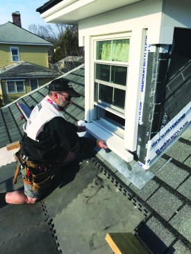 The author carefully slides the new PVC sill into position below the replacement window and the side casings.