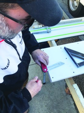 He places the bevel gauge against the edge of a straight board and records the angle.
