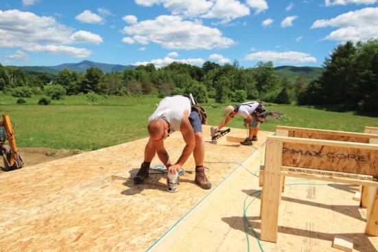 As one worker cuts out window openings, another can nail off the sheathing.