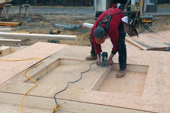 A worker using a router equipped with a bearing-guided bit cuts out a window opening. Openings can also be cut out with a circular saw or a recip saw.