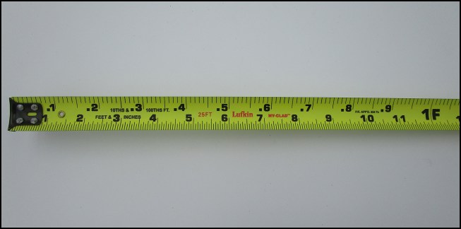 To lay out foundations, the author uses a tape measure marked with the engineer’s scale, which divides a foot into increments of 100 rather than inches. This tape also has a standard scale marked along the bottom edge.