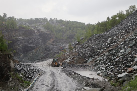 Extracting slate from the earth is still done from an open mine called a “pit”. Access roads allow for safer mining—gone are the days of workers having to climb in and out of the pit on rickety, makeshift ladders. Waste rock or “rubbish” is seen on the right of the photo. Manufacturing slate into products such as roof slates, floor tile, countertops, and flagstone has a 90-percent waste factor. Photo by Tim Healey with permission from Camara Slate Products