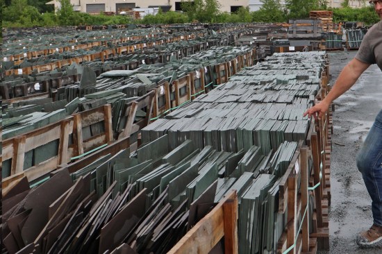 The split slate is sent to the finish mill on pallets in “chip form” (sawn on four sides to a certain length and width) ready for trimming. Here, “breakdown” pallets holding various sizes of purple slate are in the foreground and “book form” pallets of uniformly cut unfading mottled green and purple slate are in the background.