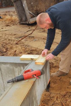 To anchor the string, we tacked two blocks to the front left corner of the house using a powder-actuated nailer. The block along the side wall was for attaching the string, and a perpendicular block on the front wall located the exact position of the string. (We always use the inside edge of the plate for our baseline.)