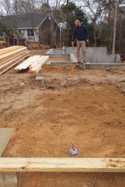 Because of the unusual jogs in the front of the house, the front of the garage was 3 feet in front of the end of the house where we'd attached our blocks, but 2 feet in back of the center section of the house. We measured back from the corner of the garage and marked the baseline location, which fell in the opening for a side door to the garage. Now we were able to stretch the baseline string over the entire length of the house.