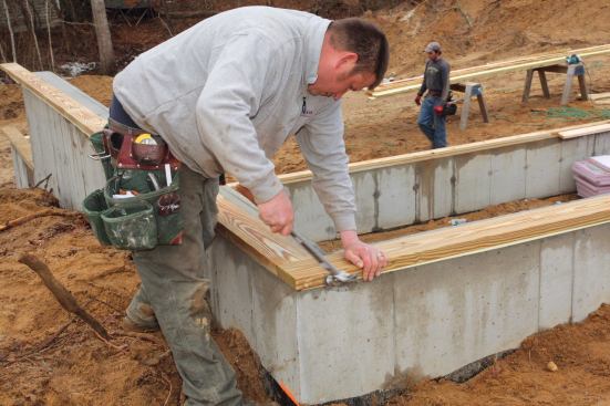 One way we sped up the final part of the layout was to attach the sill stock to the foundation of the walk-out wall before locating the key points on the wall. We let the stock run by the corner of the foundation so that we could mark the exact length of the wall directly on the sill.